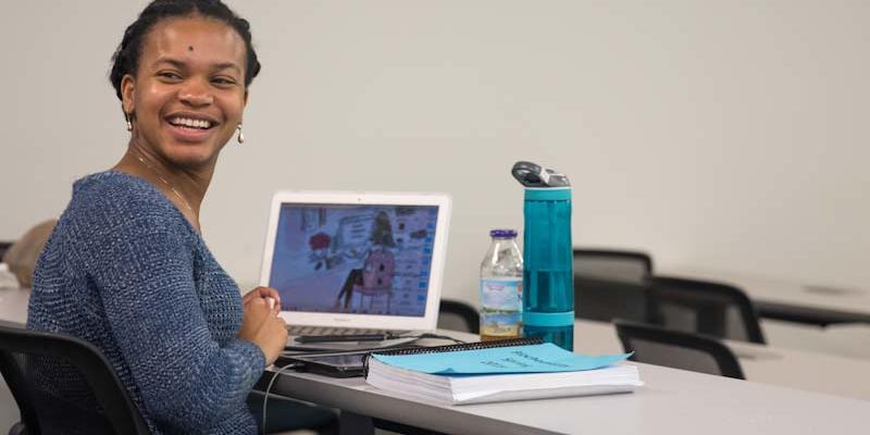 Student smiling with a computer